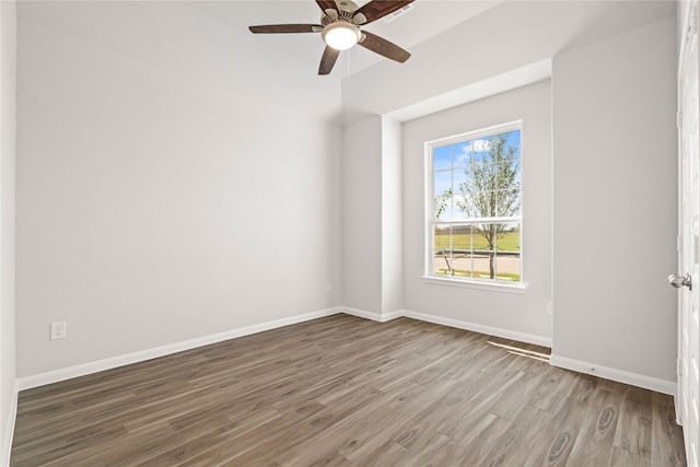 unfurnished room featuring a ceiling fan, wood finished floors, and baseboards