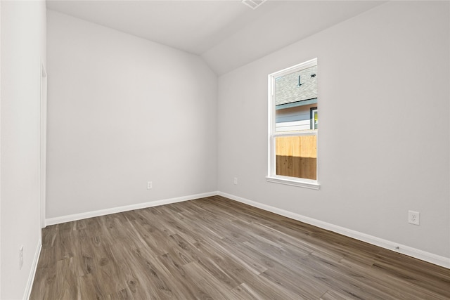 unfurnished room featuring lofted ceiling, baseboards, and wood finished floors