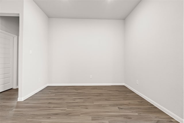 spare room featuring baseboards and wood finished floors