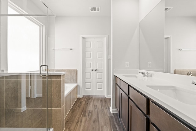 bathroom featuring a sink, a bath, visible vents, and wood finished floors