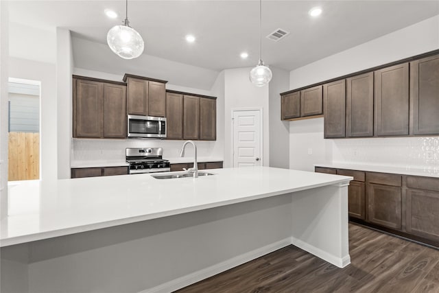 kitchen with a sink, stainless steel appliances, dark wood-type flooring, visible vents, and backsplash
