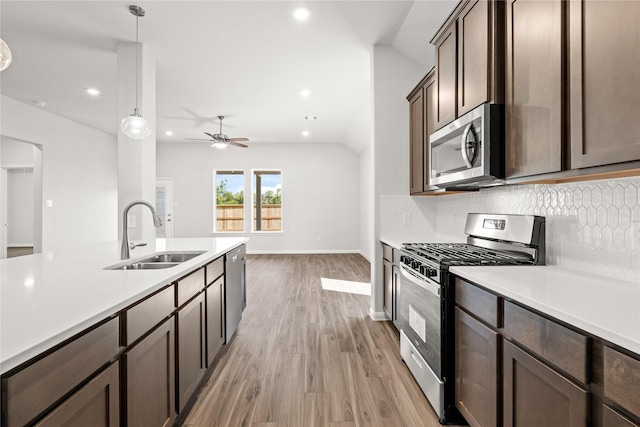 kitchen with a sink, light wood finished floors, light countertops, and appliances with stainless steel finishes