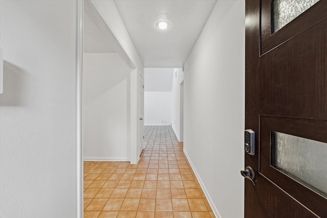 corridor featuring baseboards and light tile patterned flooring