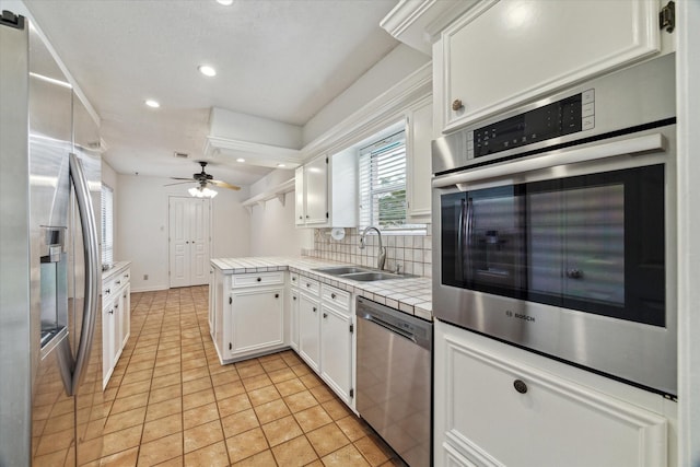 kitchen with light tile patterned floors, a sink, white cabinets, appliances with stainless steel finishes, and decorative backsplash