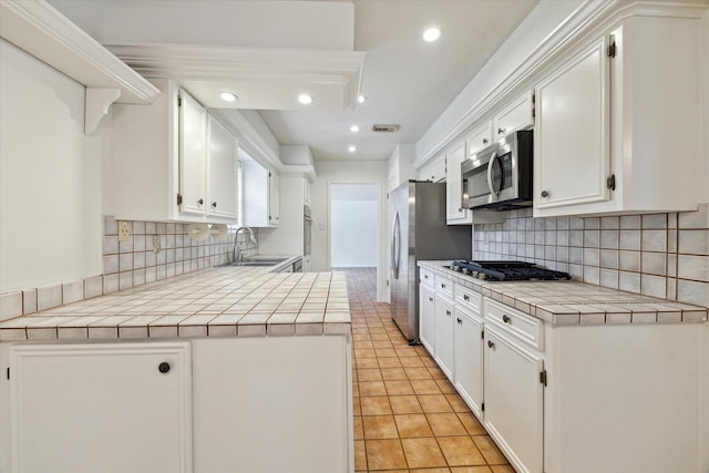 kitchen featuring a sink, stainless steel appliances, tile counters, visible vents, and recessed lighting