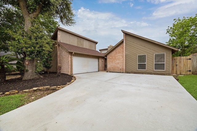 view of front of property featuring driveway, brick siding, and fence