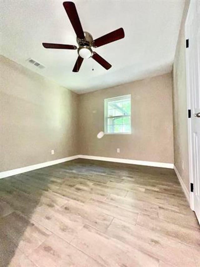 unfurnished bedroom featuring ceiling fan, baseboards, visible vents, and wood finished floors