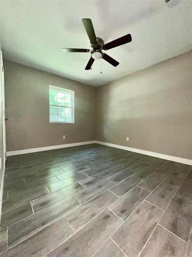 empty room featuring wood tiled floor, baseboards, and a ceiling fan