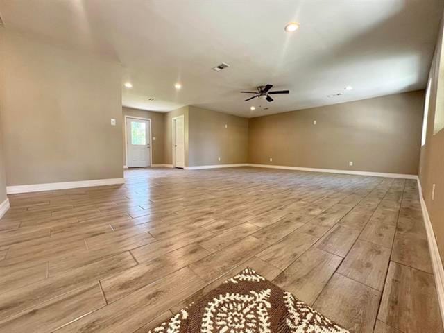 unfurnished living room with light wood finished floors, a ceiling fan, visible vents, baseboards, and recessed lighting