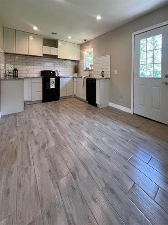 kitchen with light wood finished floors, white cabinetry, baseboards, black appliances, and tasteful backsplash