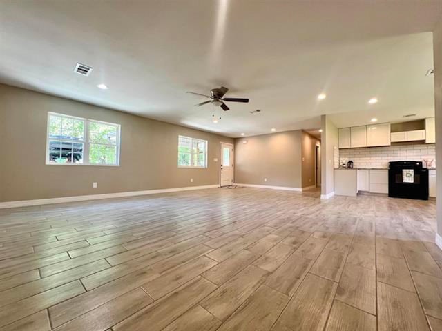 unfurnished living room featuring baseboards, a ceiling fan, wood finish floors, and recessed lighting