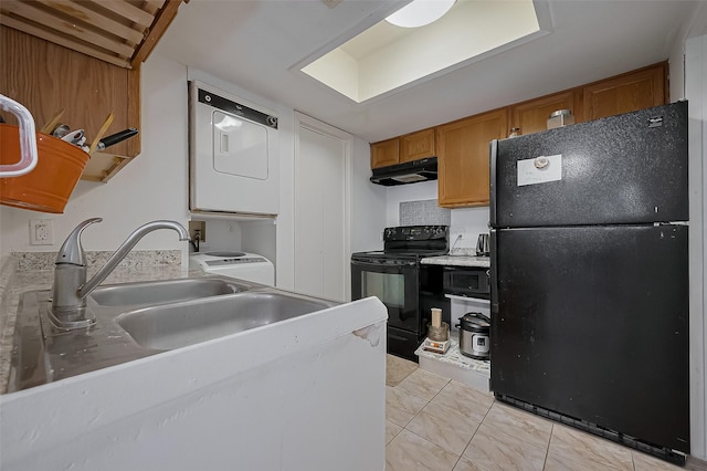 9009 Richmond Ave Unit 613, Houston, TX 77063 - kitchen with black appliances, under cabinet range hood, stacked washer and clothes dryer, brown cabinetry, and light countertops