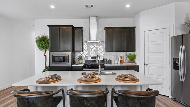 3119 Crown Gate Dr, Houston, TX 77047 - kitchen featuring light countertops, light wood-style flooring, a sink, stainless steel appliances, and wall chimney range hood