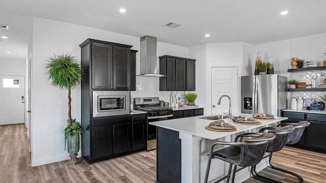 3119 Crown Gate Dr, Houston, TX 77047 - kitchen featuring a sink, wall chimney range hood, tasteful backsplash, light countertops, and appliances with stainless steel finishes