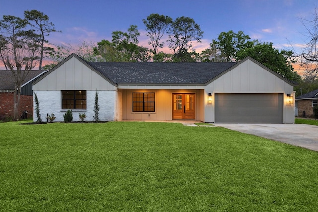 ranch-style home with concrete driveway, an attached garage, a shingled roof, and a front yard
