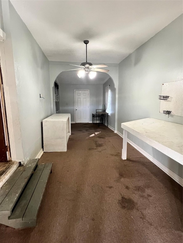 interior space featuring arched walkways, carpet floors, and baseboards