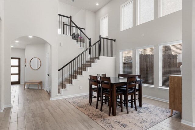 1226 Tilia Creek Ln, Montgomery, TX 77316 - dining area featuring wood finished floors, a towering ceiling, arched walkways, baseboards, and stairway