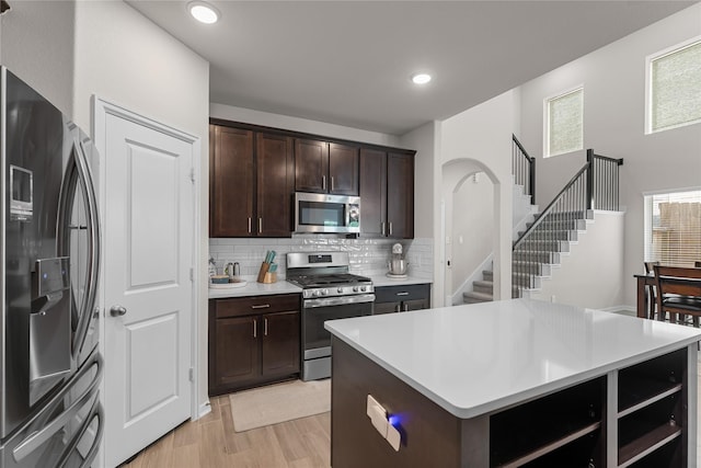 1226 Tilia Creek Ln, Montgomery, TX 77316 - kitchen with appliances with stainless steel finishes, light countertops, backsplash, dark brown cabinets, and light wood finished floors