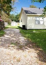 view of side of home featuring an outdoor structure, a lawn, and a shed