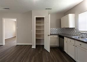 kitchen featuring dishwasher, visible vents, dark countertops, tasteful backsplash, and dark wood-style floors