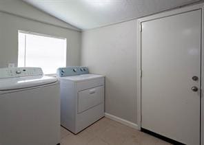 clothes washing area with baseboards, laundry area, and washer and clothes dryer