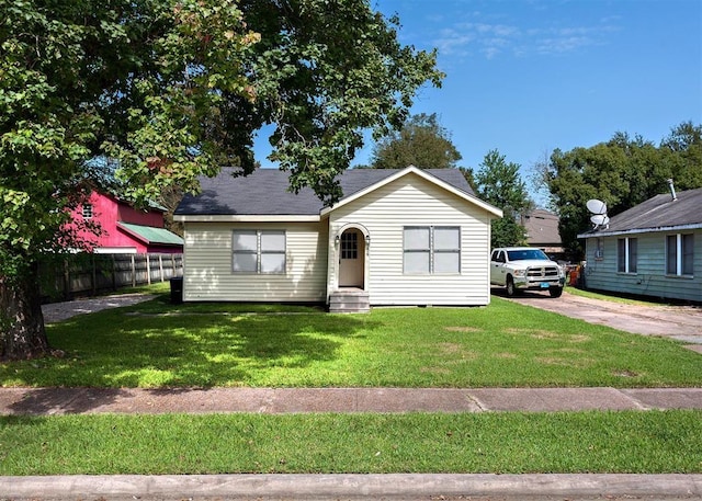 bungalow-style home featuring a front lawn, fence, and entry steps
