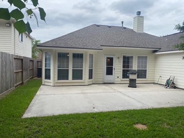 back of property featuring fence, a shingled roof, a patio, and a chimney