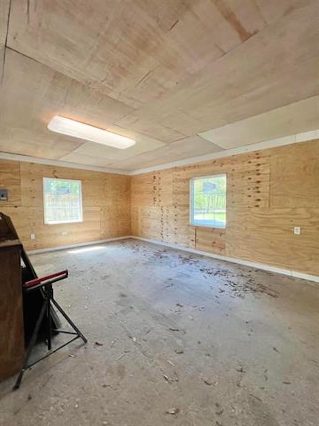 unfurnished room featuring plenty of natural light, wood ceiling, and wooden walls