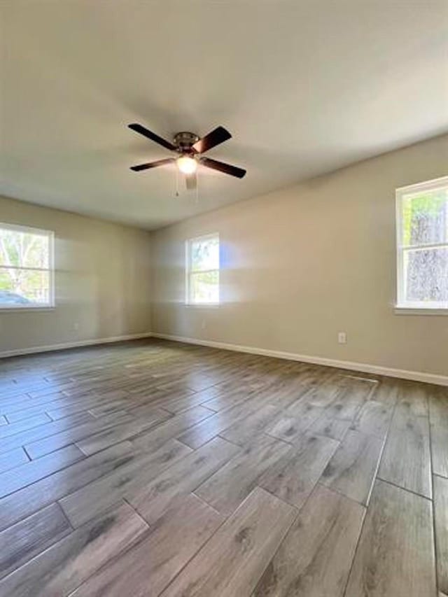unfurnished room featuring wood finished floors, baseboards, and ceiling fan