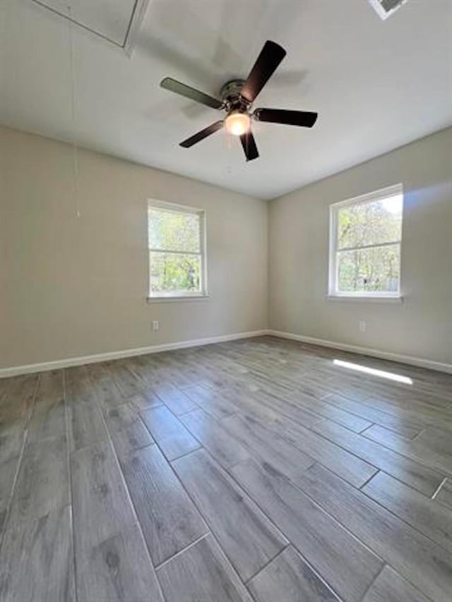 spare room featuring wood finished floors, baseboards, and a ceiling fan