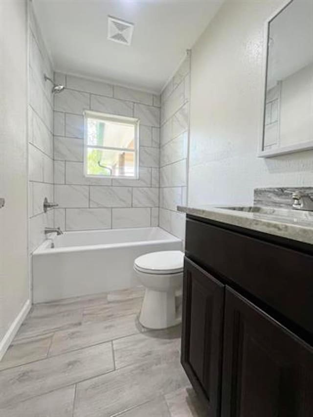 bathroom featuring toilet, vanity, bathtub / shower combination, and baseboards