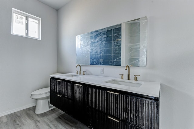 full bath featuring double vanity, toilet, wood finished floors, and a sink