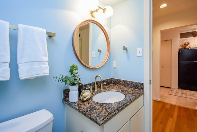 half bath featuring toilet, vanity, recessed lighting, and wood finished floors