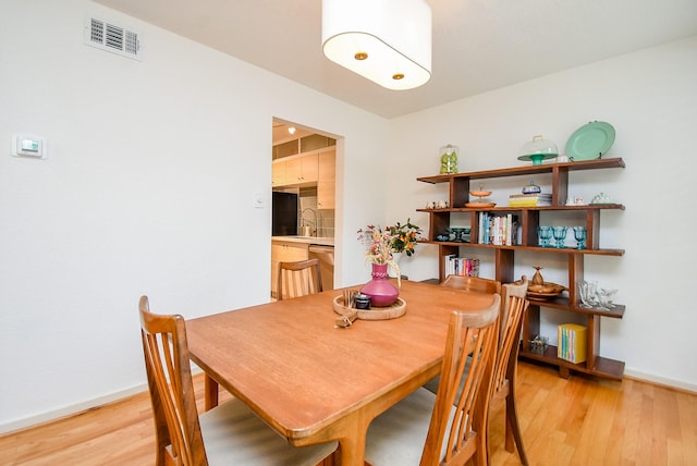 dining room featuring baseboards, light wood-type flooring, and visible vents