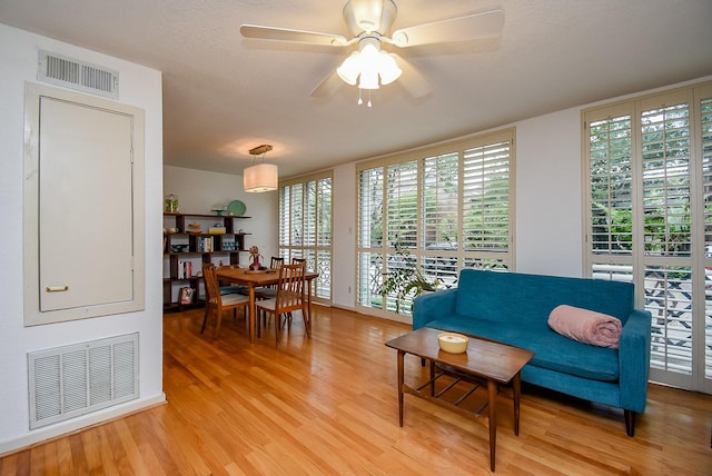 living area with light wood-style floors, visible vents, a healthy amount of sunlight, and ceiling fan