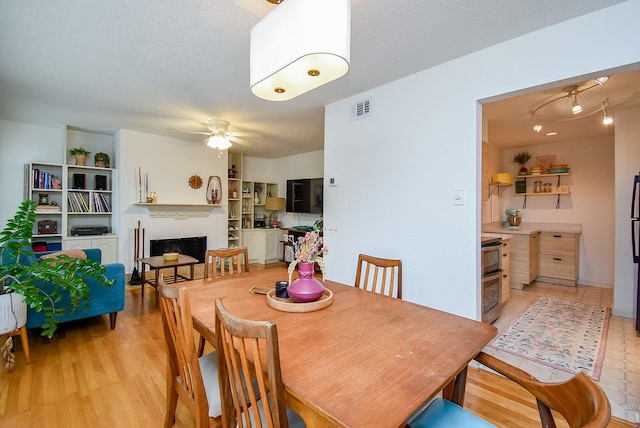 dining space featuring a fireplace, a ceiling fan, and visible vents