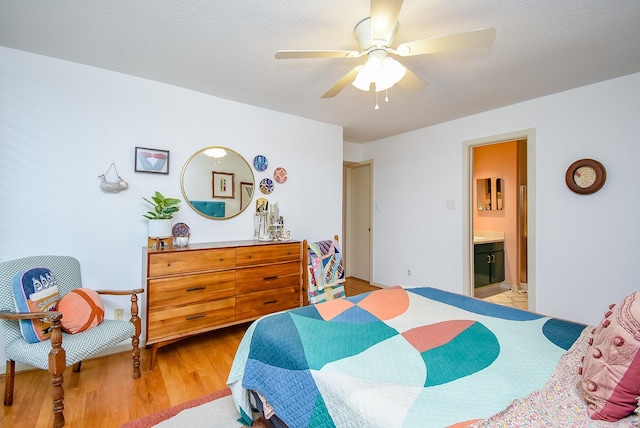 bedroom with light wood finished floors, ensuite bathroom, and ceiling fan