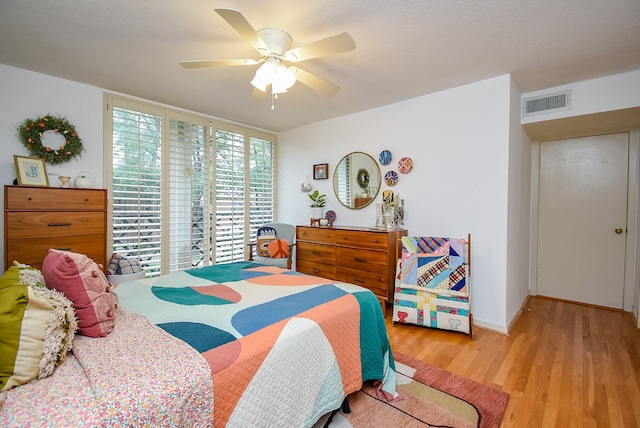 bedroom featuring ceiling fan, baseboards, visible vents, and wood finished floors