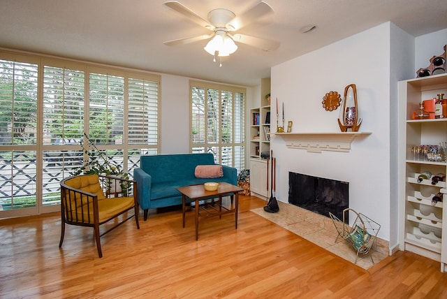 sitting room featuring light wood-style floors, a tile fireplace, and ceiling fan
