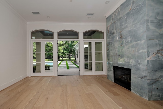 unfurnished living room with wood finished floors, ornamental molding, visible vents, a fireplace, and baseboards