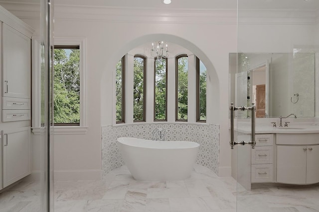 full bathroom with a soaking tub, baseboards, a chandelier, vanity, and ornamental molding