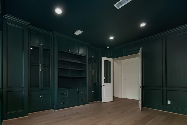 interior space with light wood-type flooring, visible vents, a decorative wall, ornamental molding, and recessed lighting