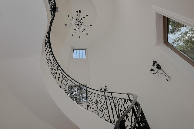 stairway featuring a chandelier and a towering ceiling