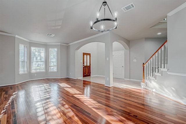 unfurnished living room featuring a chandelier, wood-type flooring, arched walkways, and visible vents