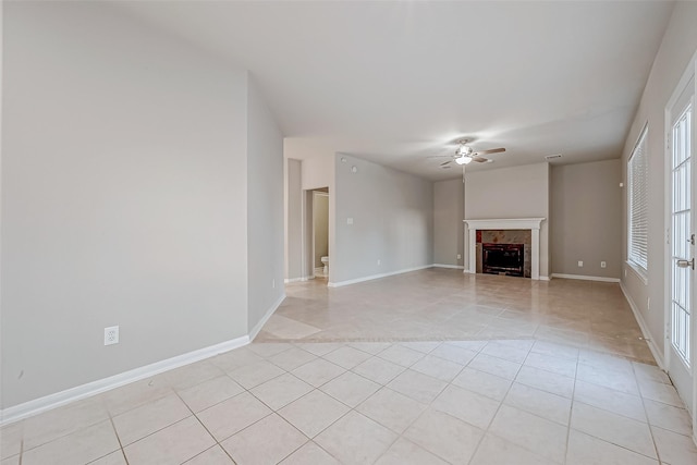 unfurnished living room with light tile patterned floors, a healthy amount of sunlight, a fireplace, and a ceiling fan