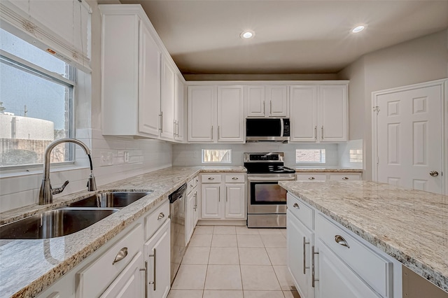 kitchen featuring a sink, stainless steel appliances, backsplash, and white cabinetry