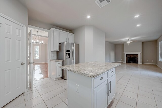 kitchen with stainless steel fridge with ice dispenser, light tile patterned floors, visible vents, and ceiling fan with notable chandelier
