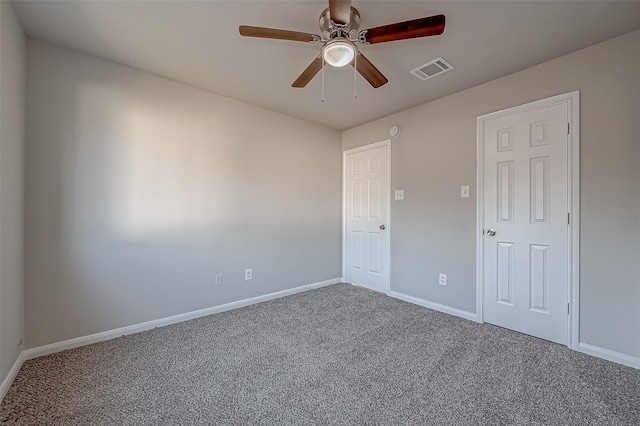 carpeted spare room with visible vents, baseboards, and a ceiling fan