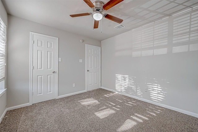 unfurnished bedroom featuring carpet, baseboards, a ceiling fan, and visible vents