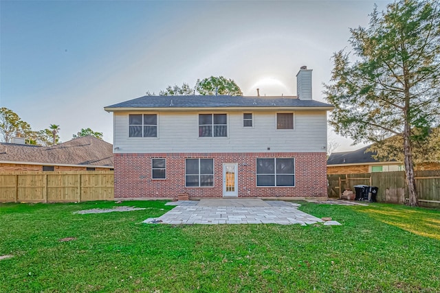 back of house featuring a lawn, a patio area, brick siding, and a fenced backyard